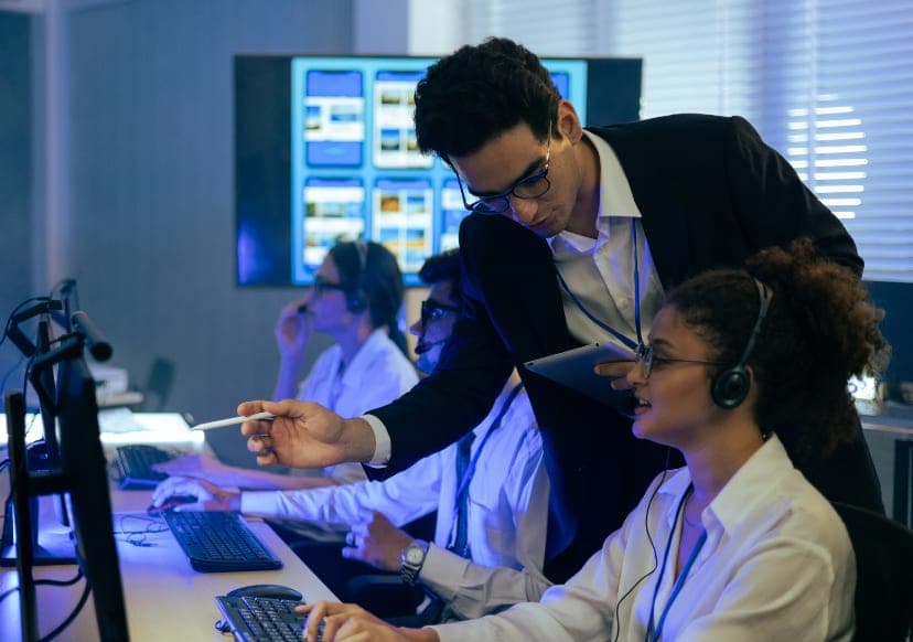 Team leader coaching an agent alongside quality dashboards